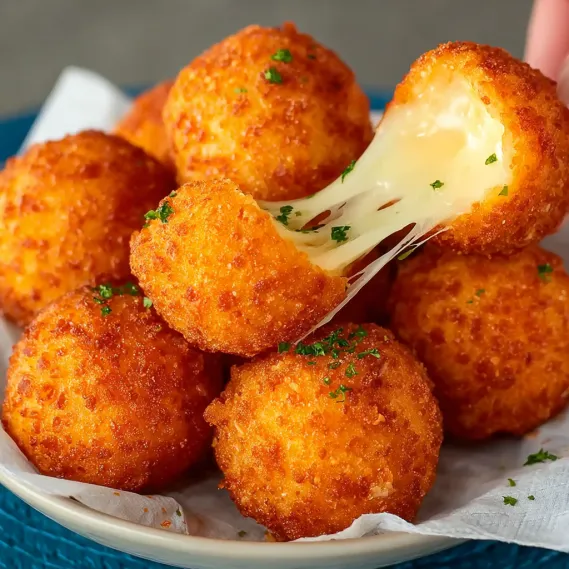 A plate of fried cheese balls with cheese dripping off.