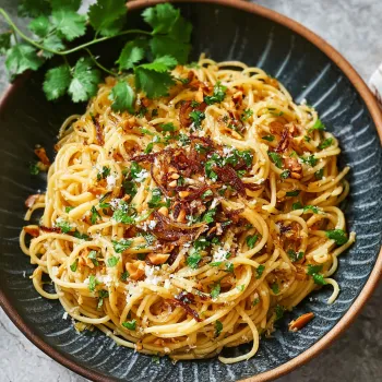 A bowl of noodles with vegetables and herbs.
