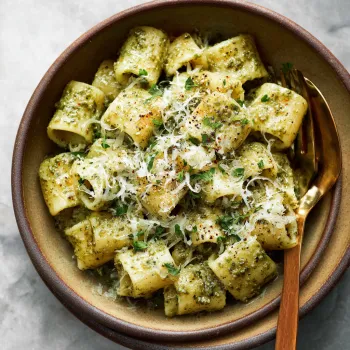A bowl of pasta with pesto sauce.