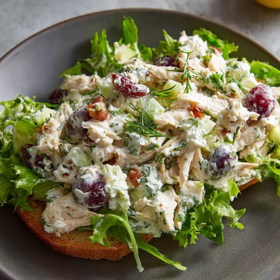 A plate of chicken salad with lettuce and grapes.