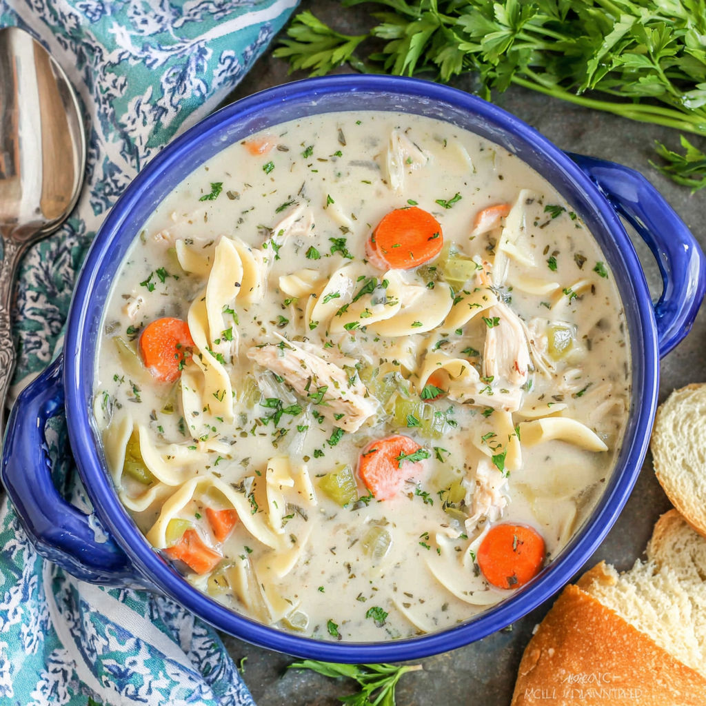 A bowl of soup with carrots and chicken.