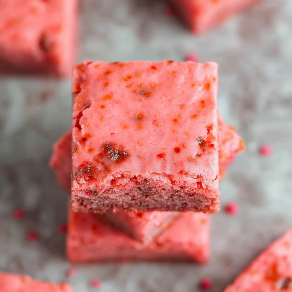 A piece of pink cake with red and brown toppings.
