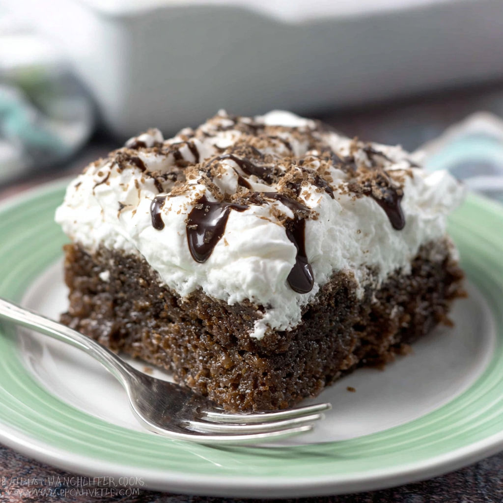 A slice of cake with white frosting and chocolate drizzle.