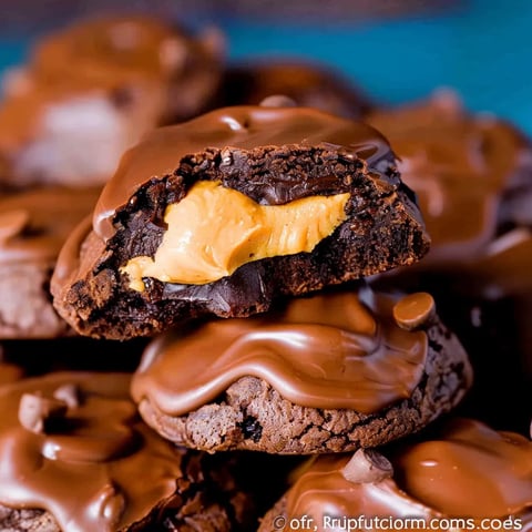 A close up of a chocolate covered cookie with peanut butter in the middle.