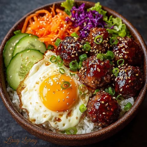 A bowl of food with meatballs, rice, and vegetables.