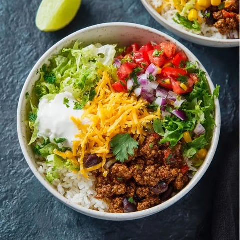 A bowl of ground beef burrito with rice and tomatoes.