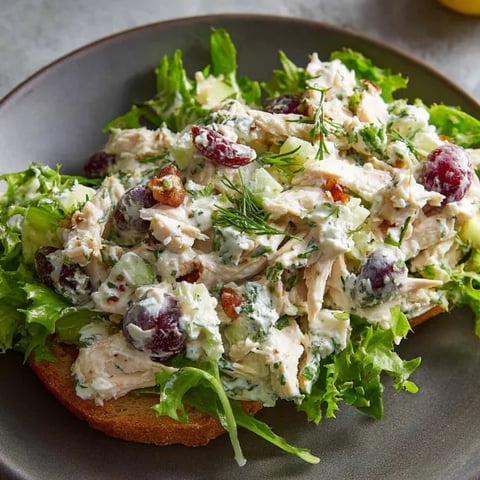 A plate of chicken salad with lettuce and grapes.