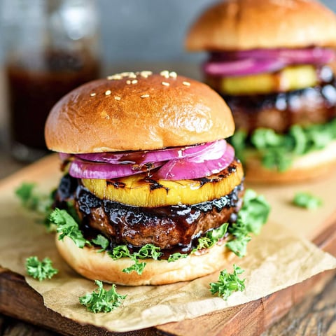 Two Hawaiian teriyaki beef burgers on a wooden table.