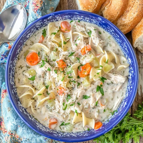 A bowl of creamy chicken noodle soup with vegetables.