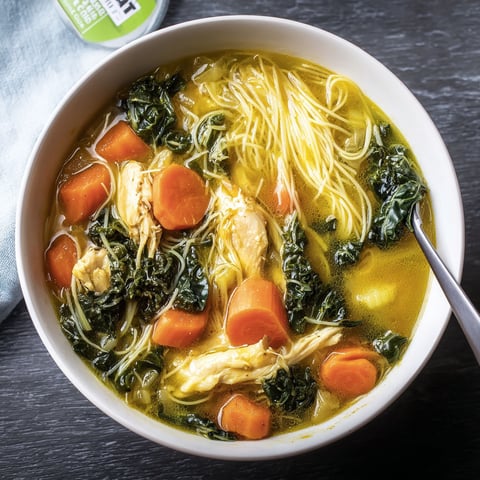 A bowl of soup with carrots and noodles.