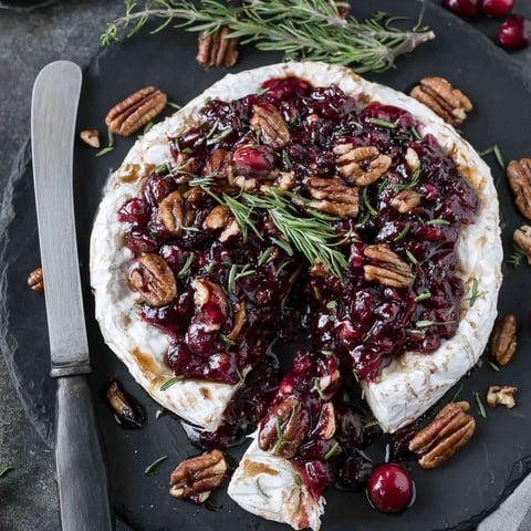 A slice of baked brie with cranberries and pecans.