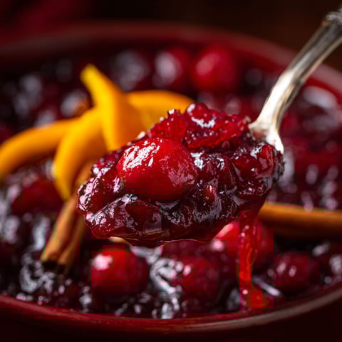 A spoon is in a bowl of cranberry sauce.