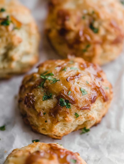 A close up of a biscuit with caramelized onions and gruyere cheese.