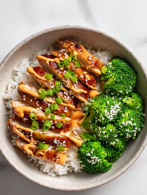 A bowl of rice and chicken with sauce.