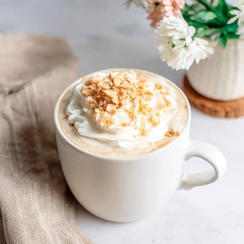 A cup of Caramel Brûlée Latte with whipped cream.