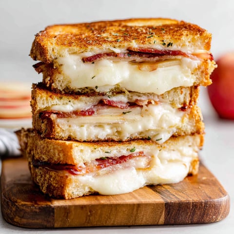 A grilled cheese sandwich with bacon and an apple slice.