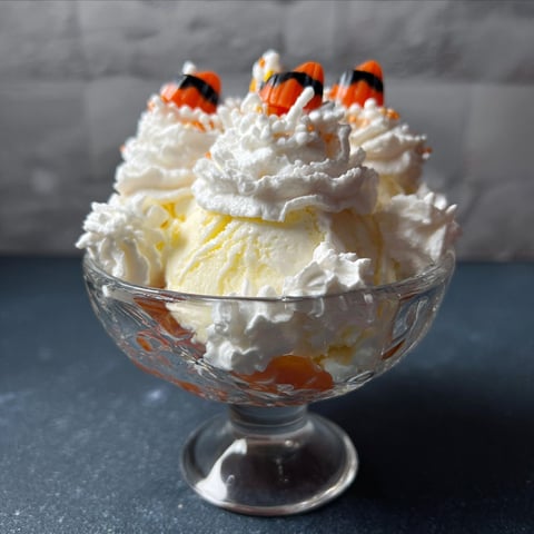 A fake corn ice cream sundae in a glass bowl.